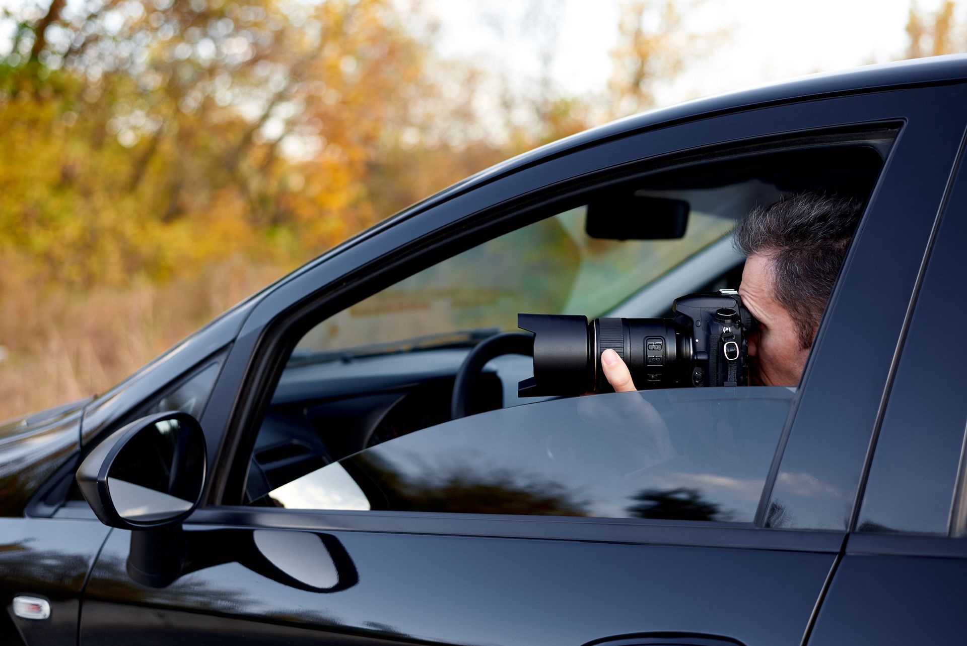An investigator is in a car with a camera