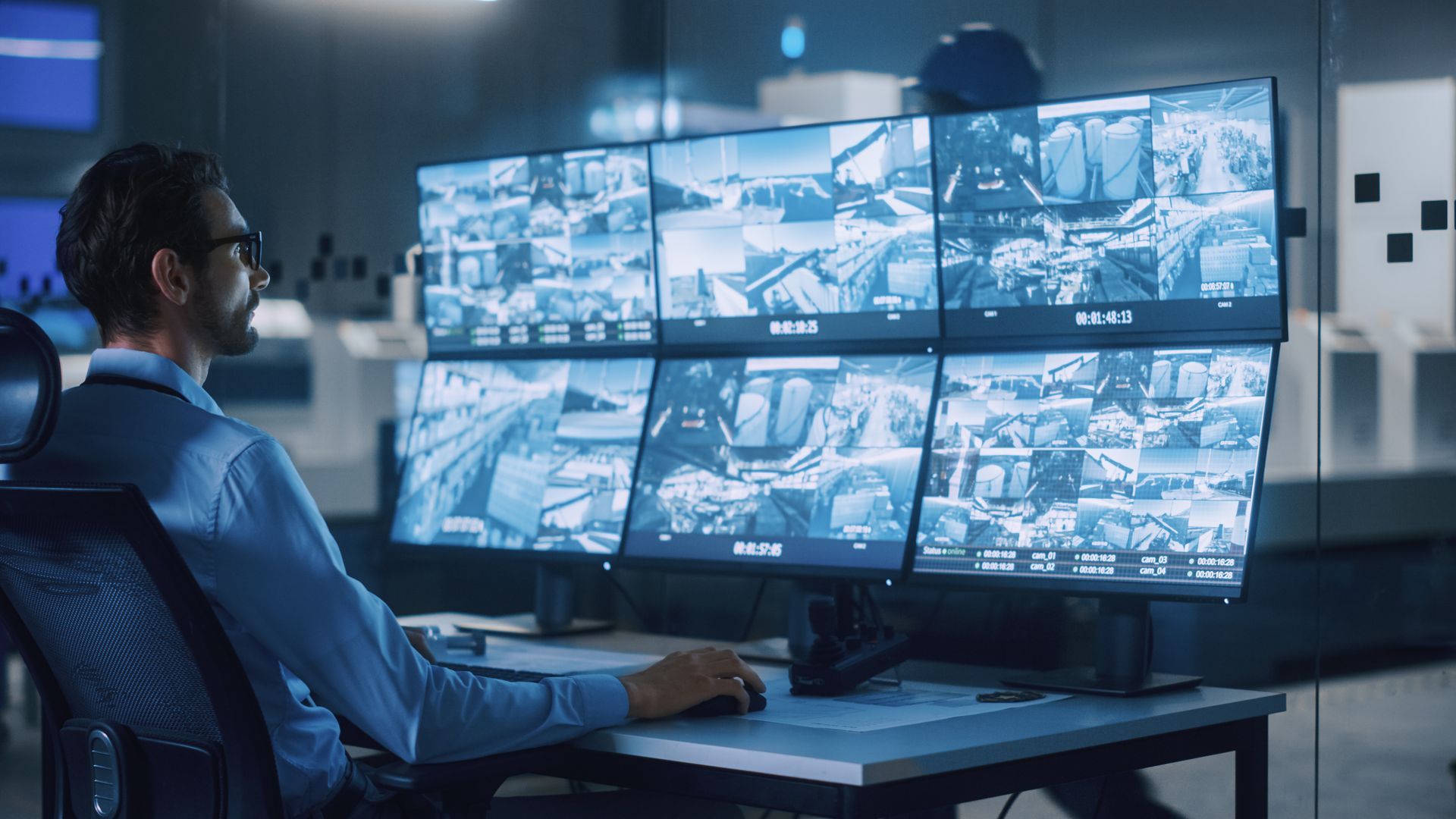 A security officer controls CCTV cameras, using computers with surveillance footage.