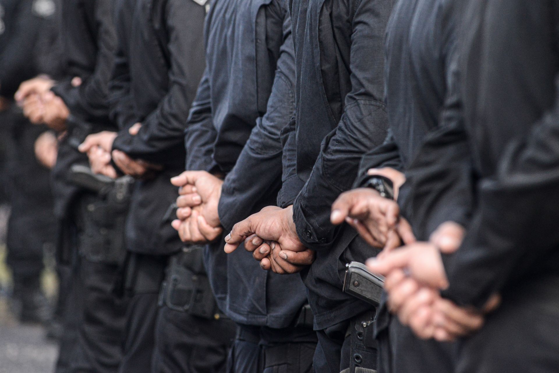 Armed security officers standing in formation with hands behind backs.
