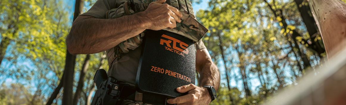 Person holding a black bucket with orange text, outside with trees in the background.