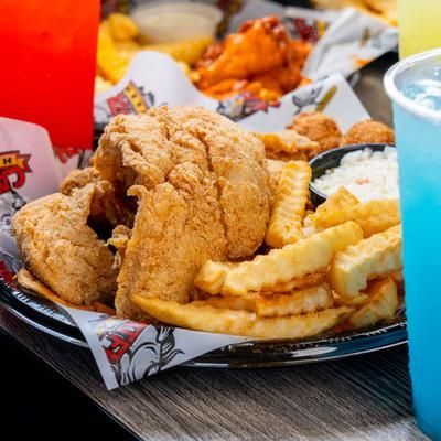 A plate of fried chicken , french fries , and wings on a table.