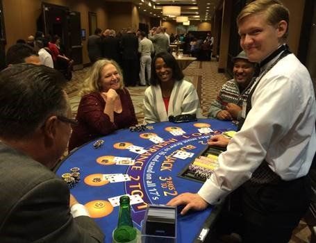 A group of people are sitting around a blackjack table.