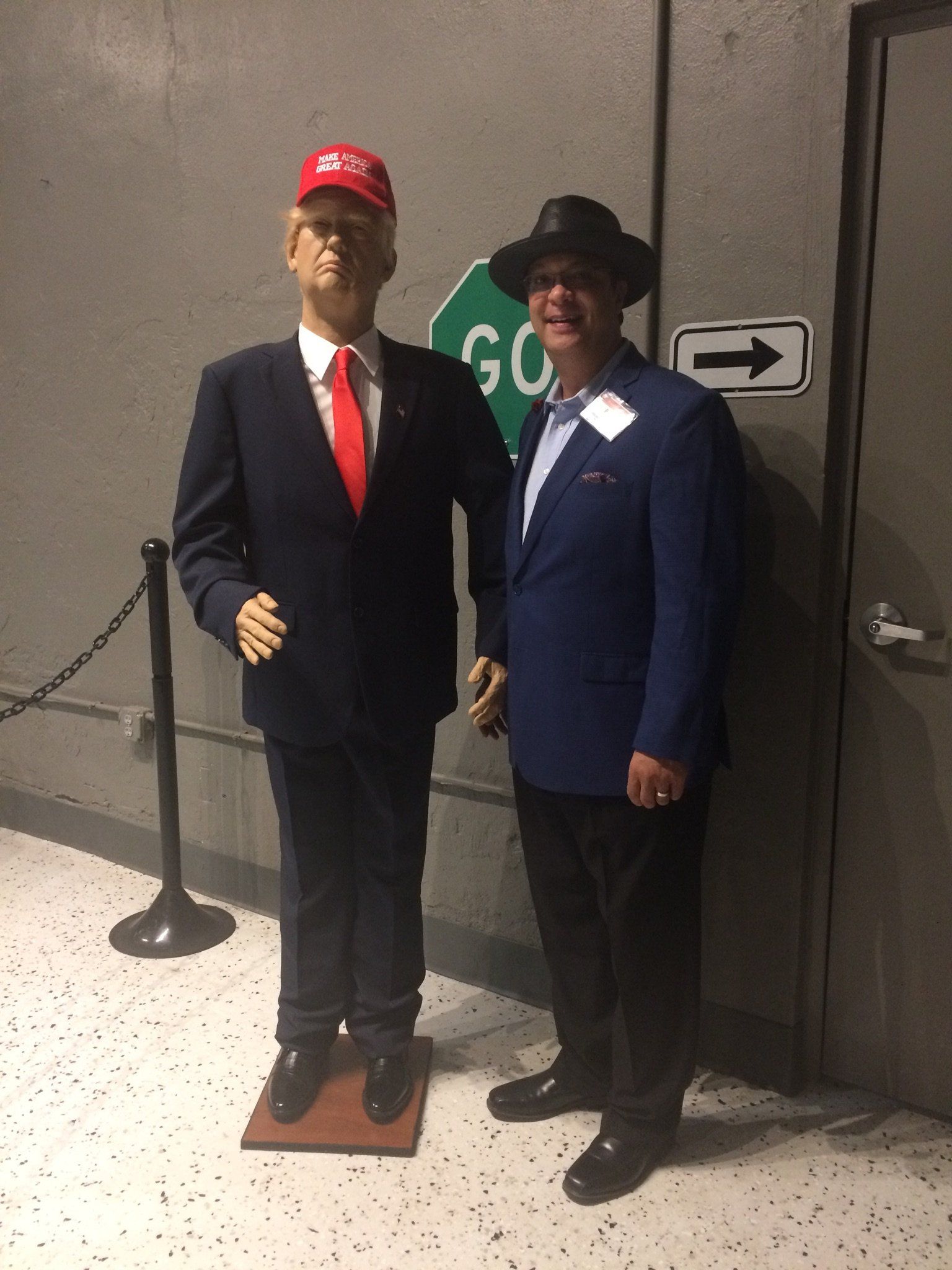 Man standing next to a wax bust of Donald Trump