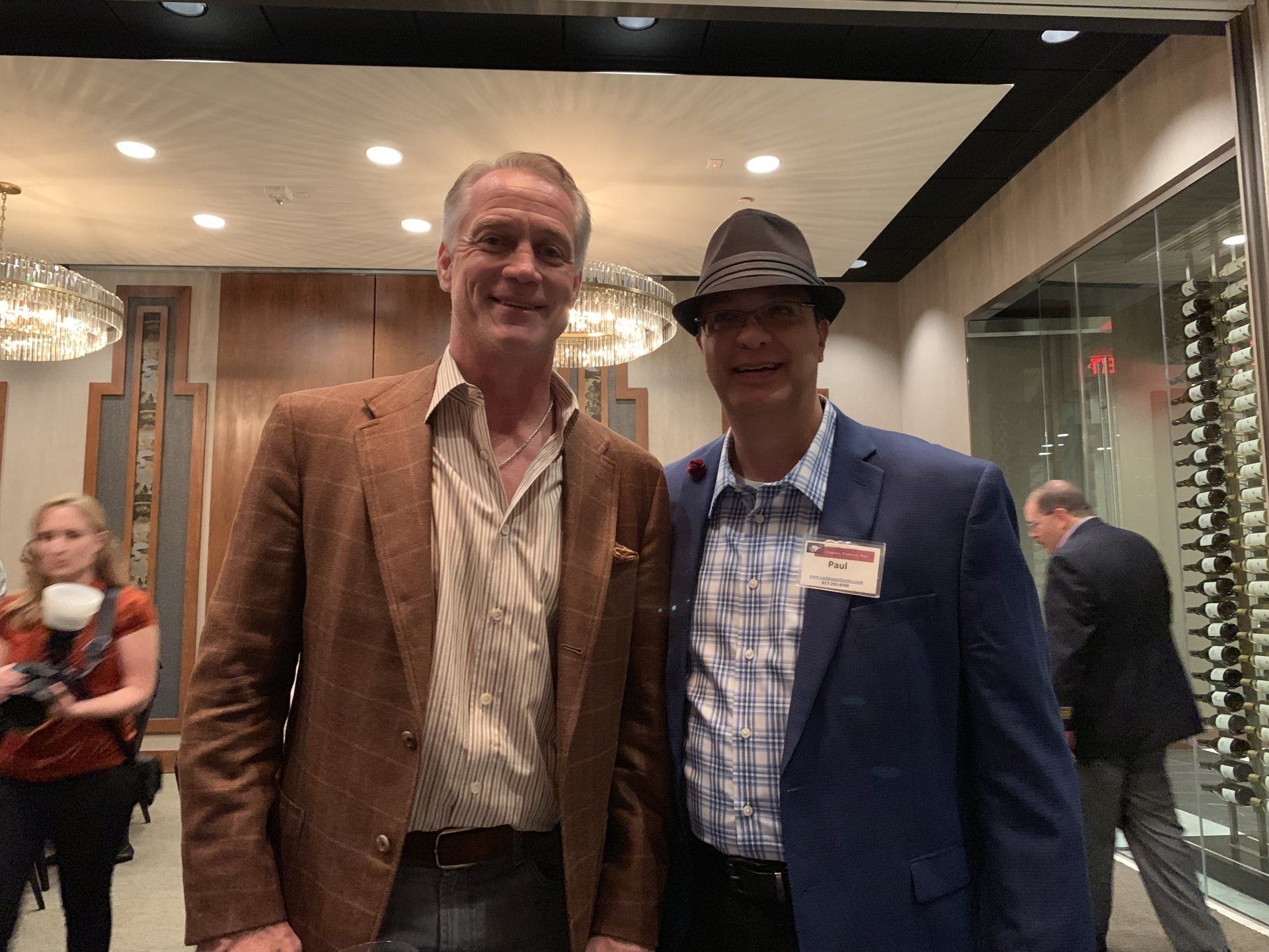 Two men in suits and hats are standing next to each other in a room.
