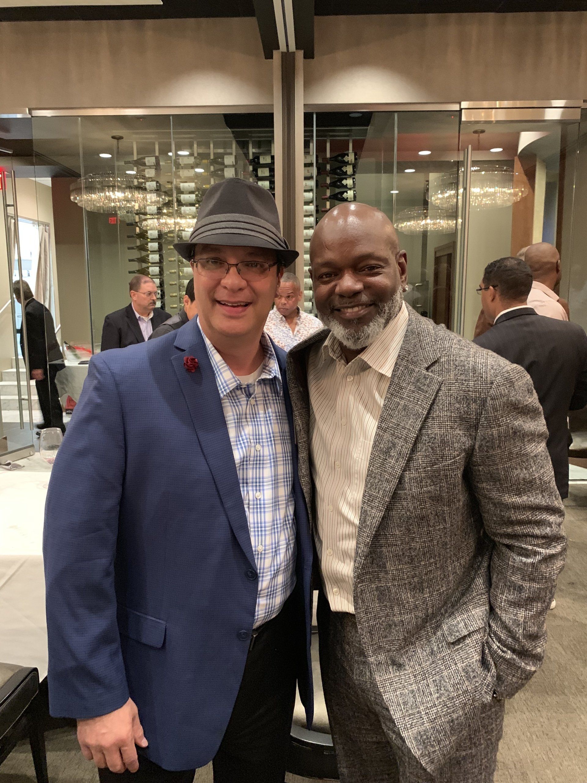 Two men in suits and hats are posing for a picture