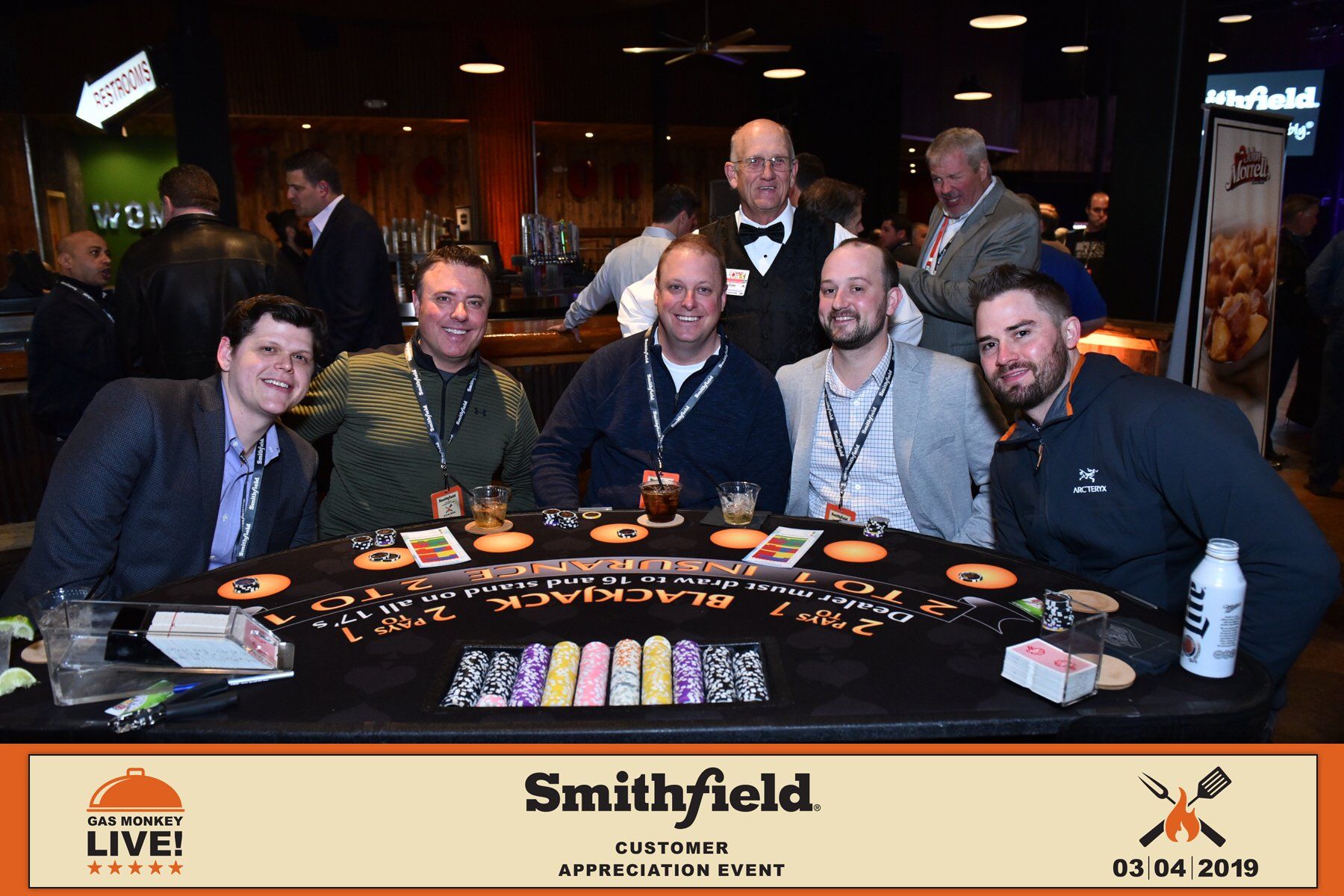A group of men are posing for a picture at a poker table.
