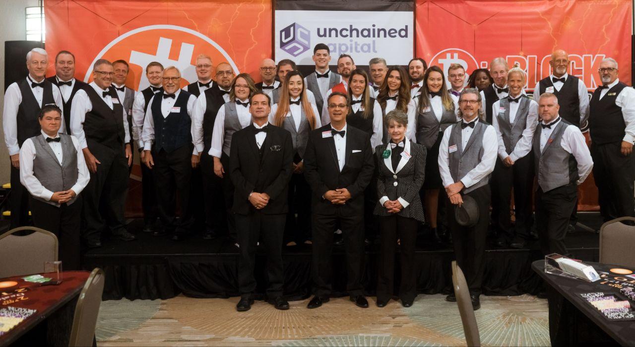 Group of people in formal attire pose on a stage with 