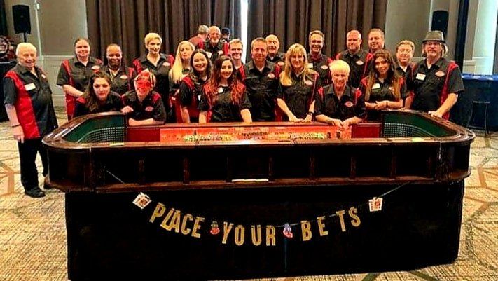 A group of people are posing for a picture in front of a roulette table.