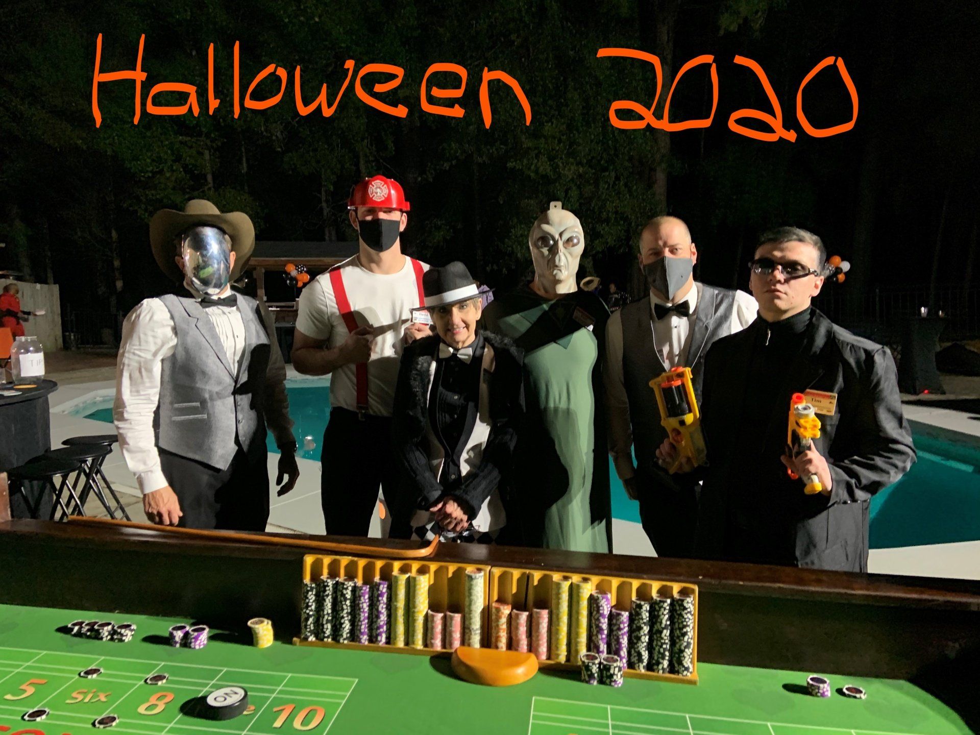 A group of men dressed in halloween costumes are standing around a roulette table.