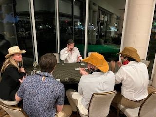 A group of people are sitting around a table playing cards.