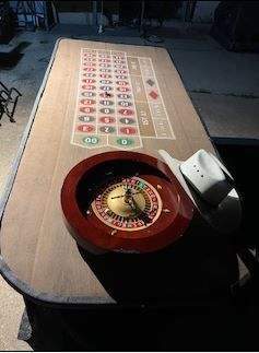 A roulette wheel is on a table next to a cowboy hat