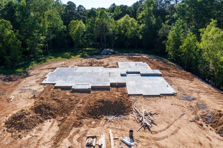 Aerial view of a building foundation slab under construction in a wooded clearing.