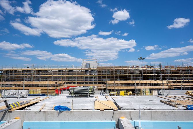 Construction site with steel scaffolding and concrete under a bright blue sky with clouds
