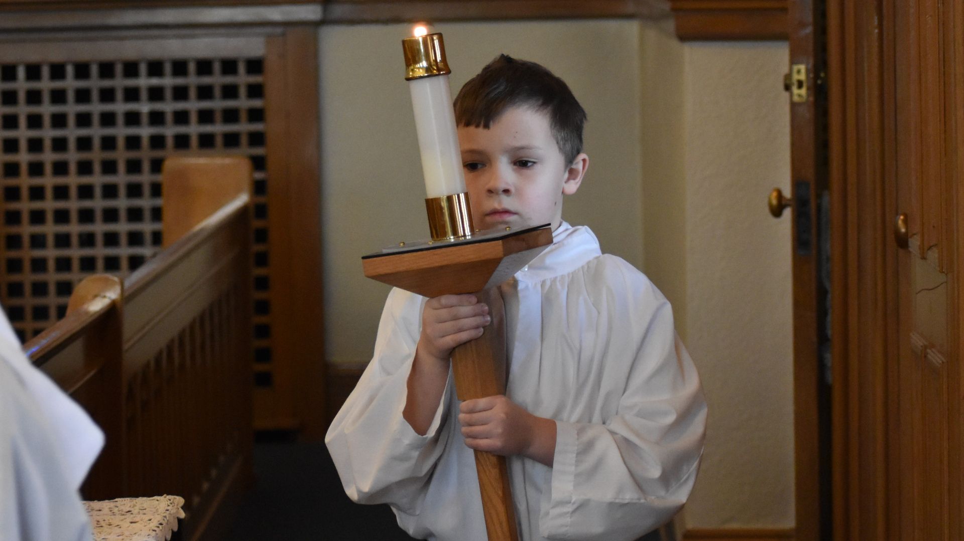 A young boy is holding a candle in a church