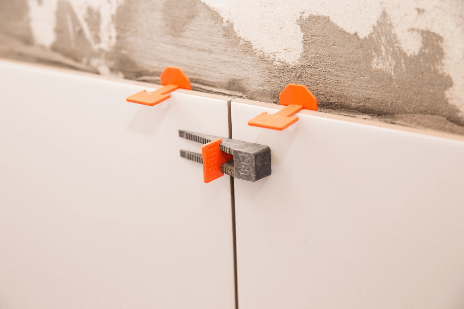 Azulejos que se instalan con clips niveladores de color naranja.