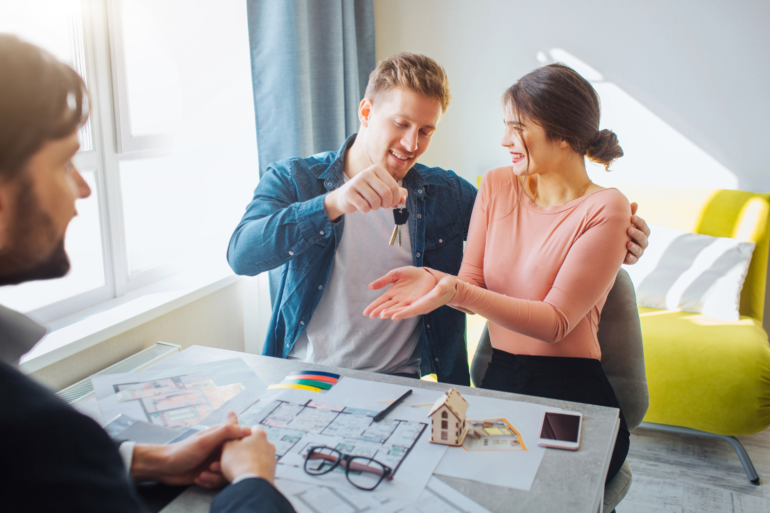 Couple receiving keys from a real estate agent, celebrating new home purchase.