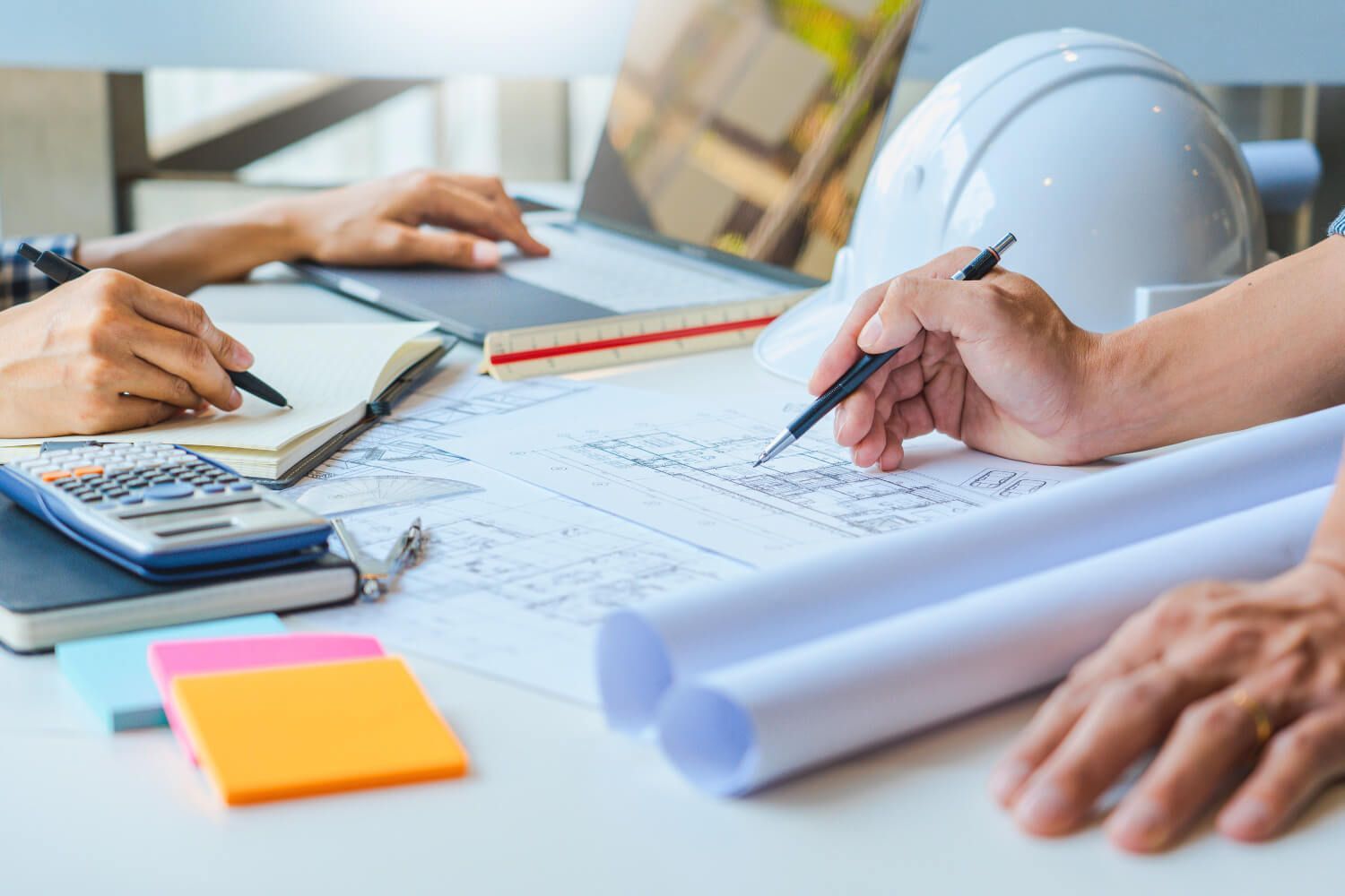 Personas revisando planos arquitectónicos en un escritorio