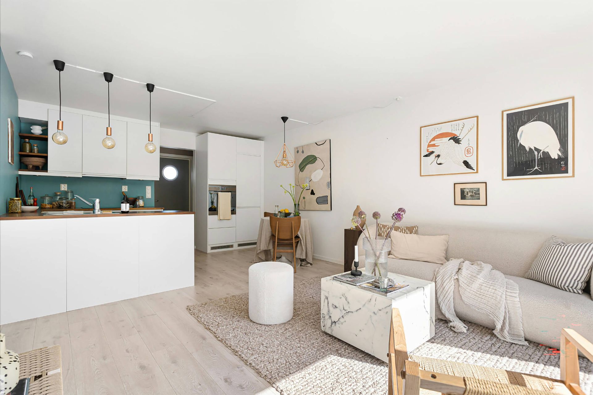 Cocina abierta al salón con diseño moderno, muebles blancos y detalles decorativos en estilo nórdico