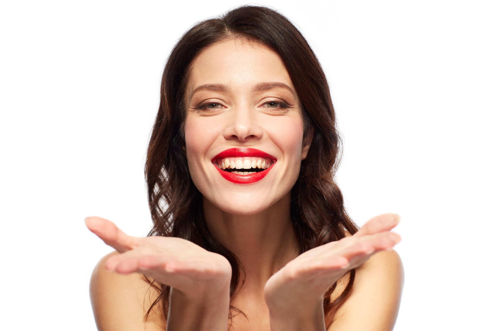 A woman with red lipstick is smiling and holding her hands up in the air.