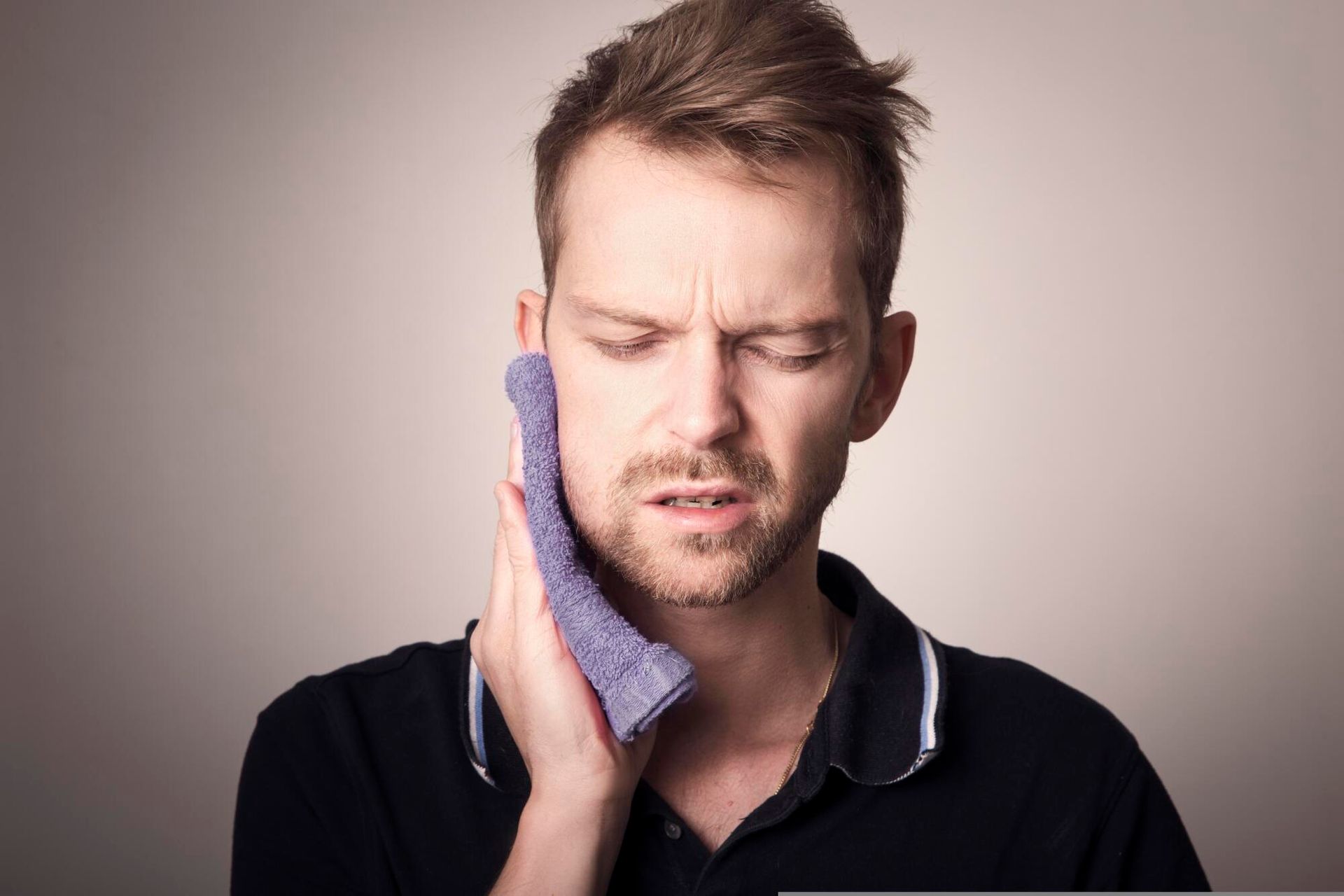 A man is holding a towel to his face because he has a toothache.