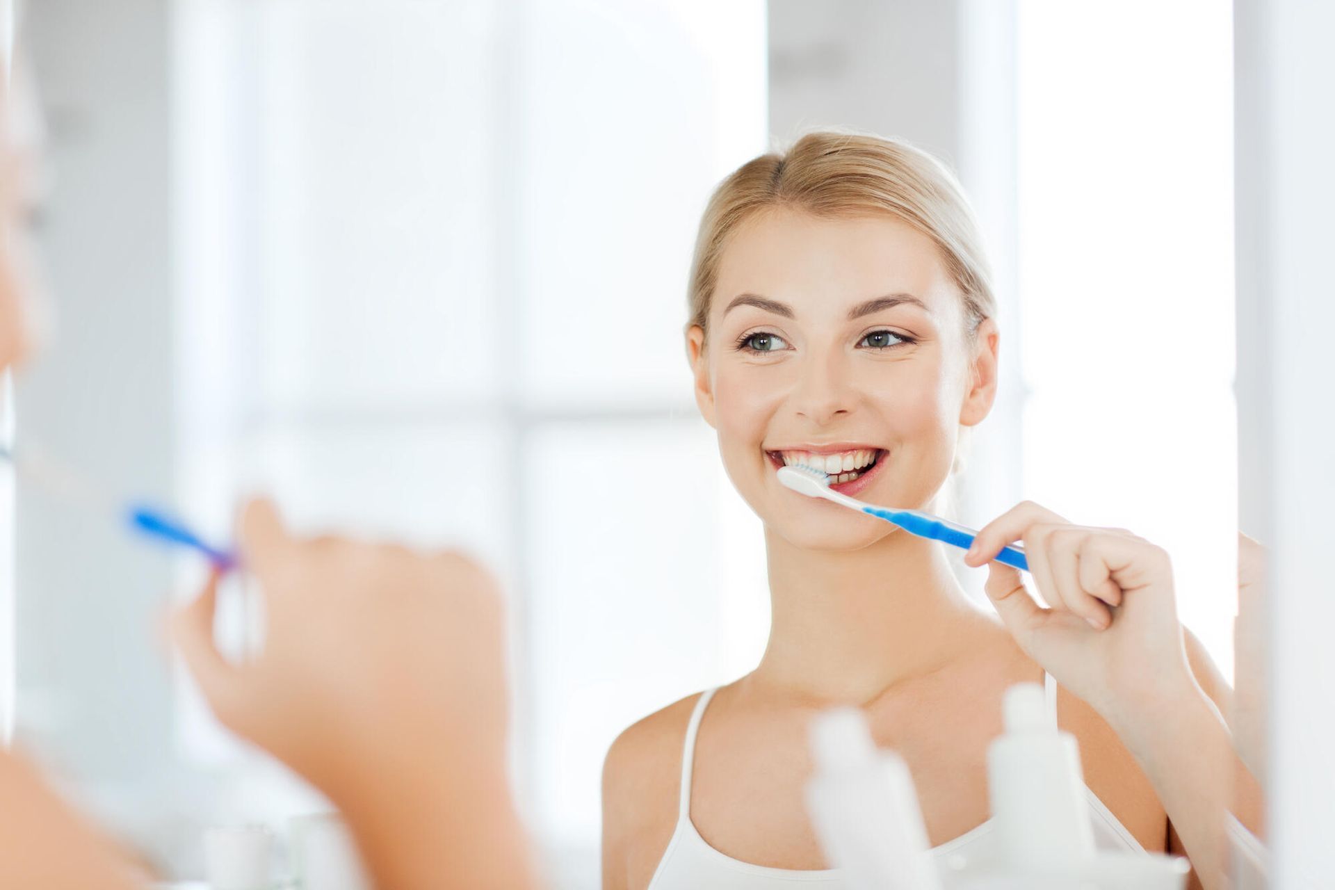 A woman is brushing her teeth in front of a mirror.