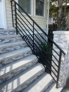 A set of stairs with a black railing leading up to a house.