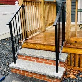 A wooden deck with brick steps and a metal railing.