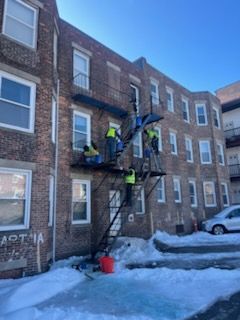 A group of people are working on a fire escape on the side of a building.