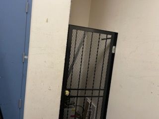 A metal gate is sitting in a corner of a room next to a blue door.