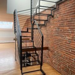 A spiral staircase in an empty room next to a brick wall.