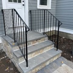 There is a black railing on the steps of a house.
