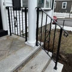 A black wrought iron railing on the steps of a house.