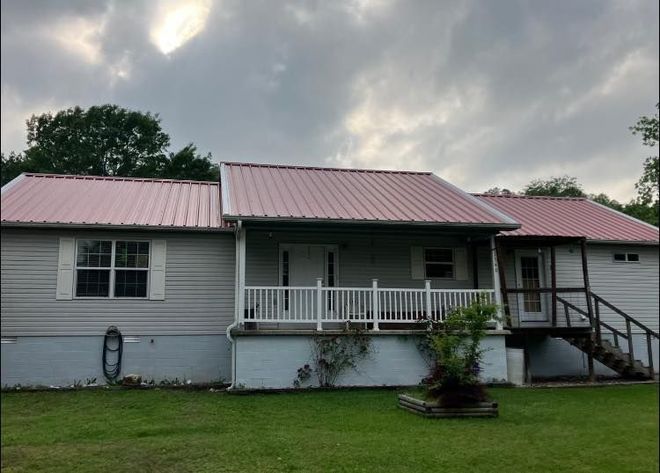 A white house with a pink metal roof