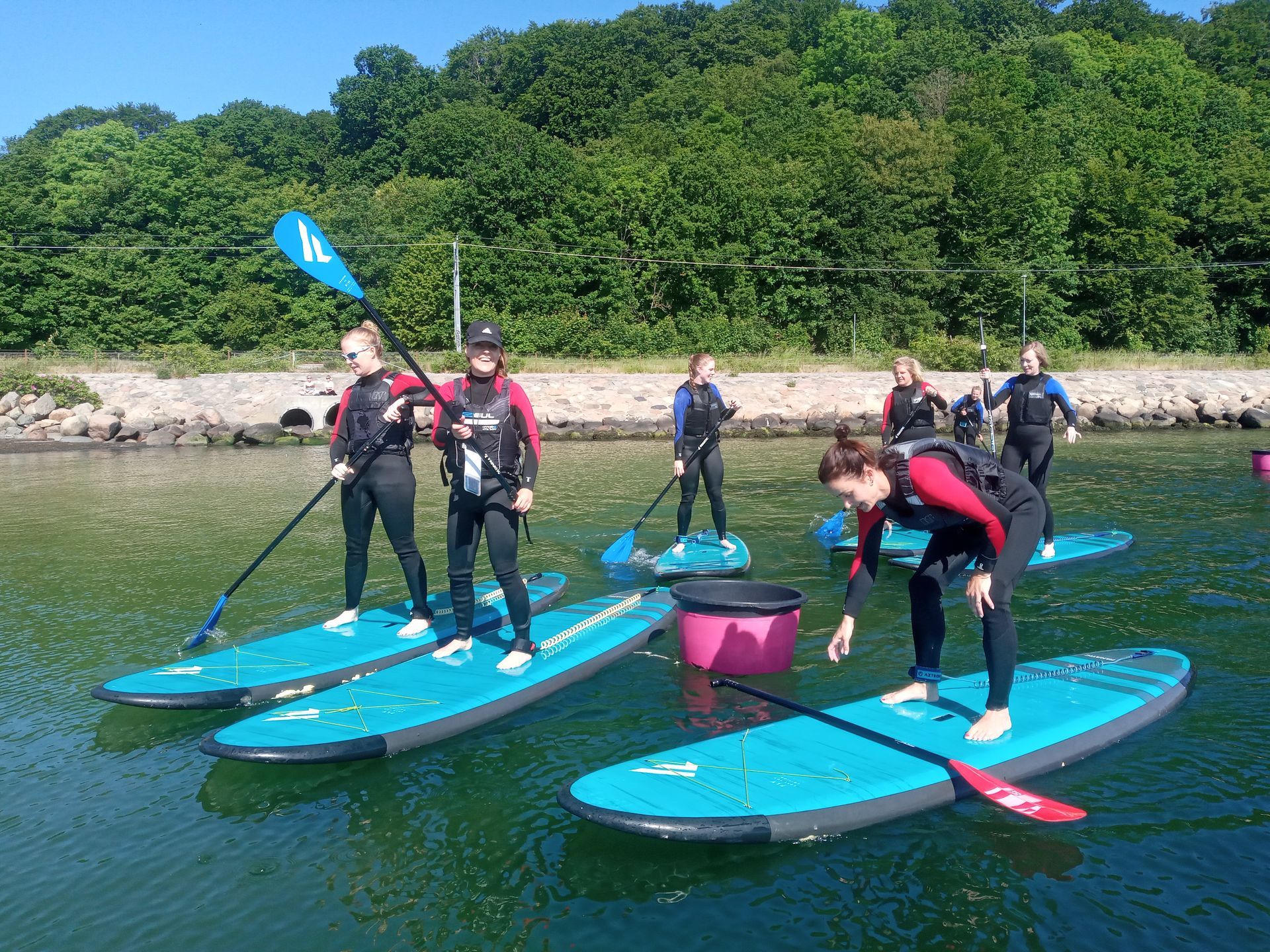 En gruppe mennesker står på paddleboards i vandet.