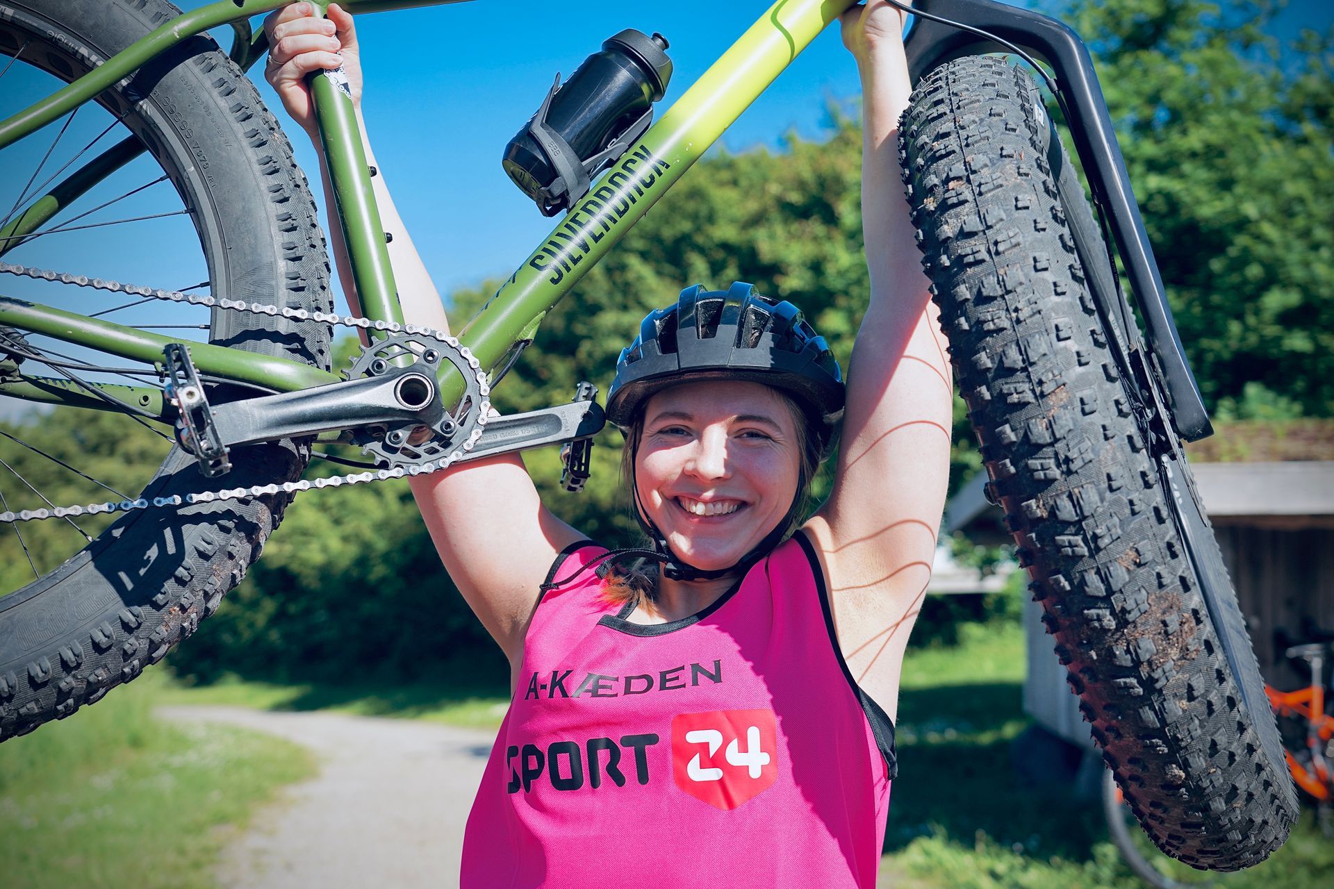 Silhuetter af cyklister på cykler mod en solnedgang over vandet.