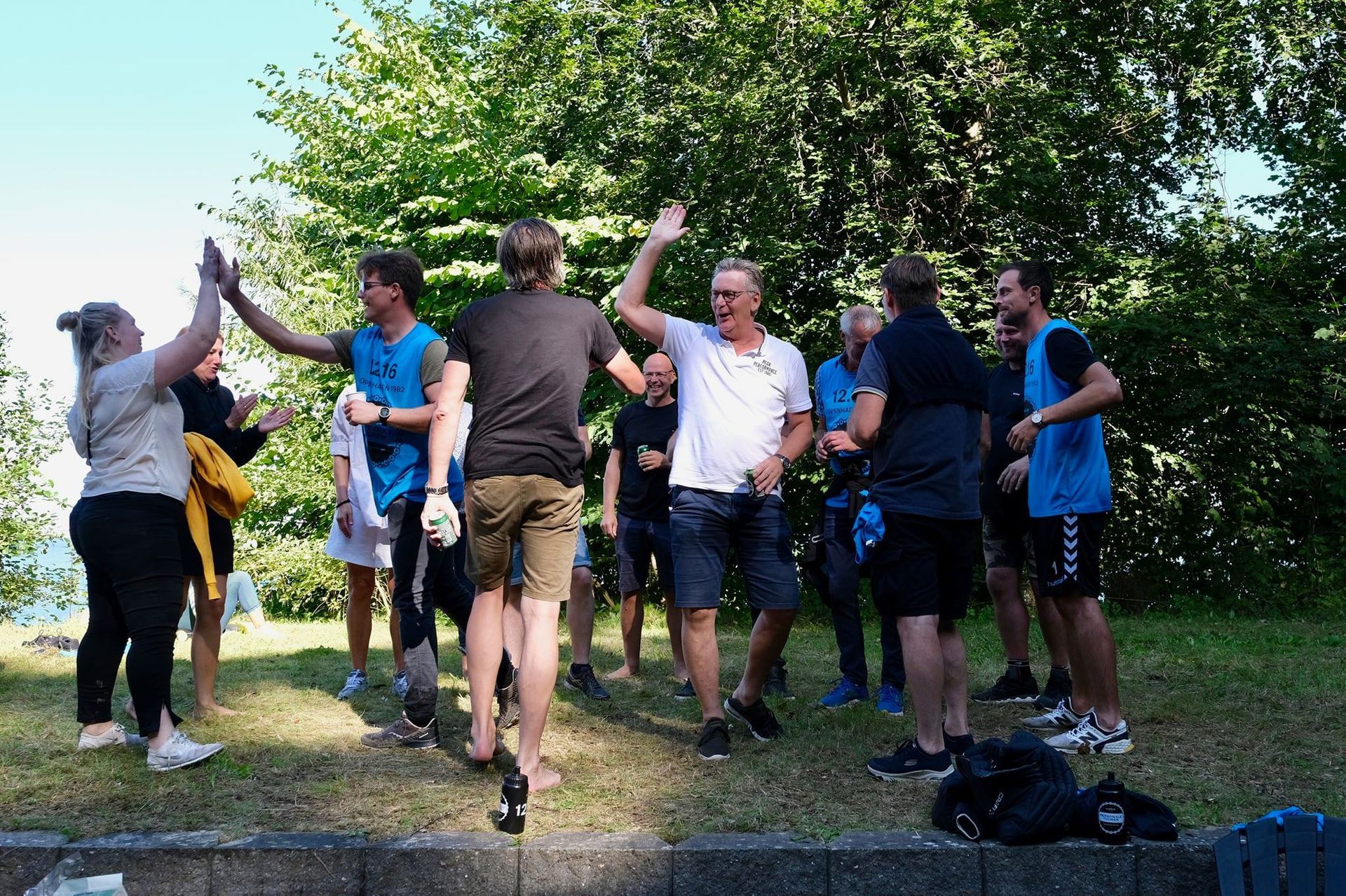 En gruppe mennesker står på en mark og giver hinanden high fives.