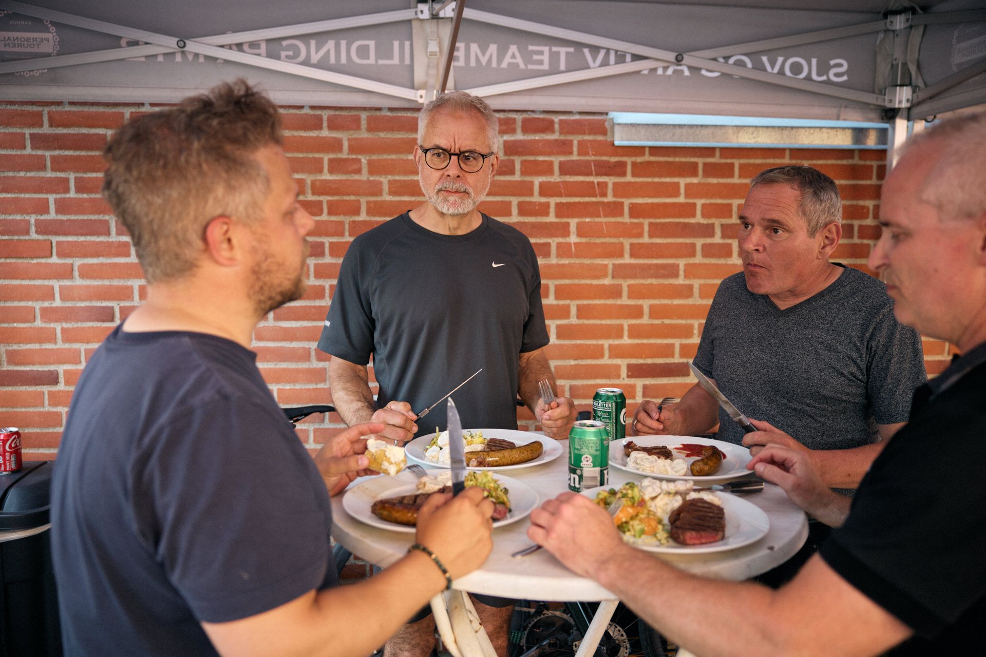 En gruppe mænd sidder omkring et bord og spiser mad.