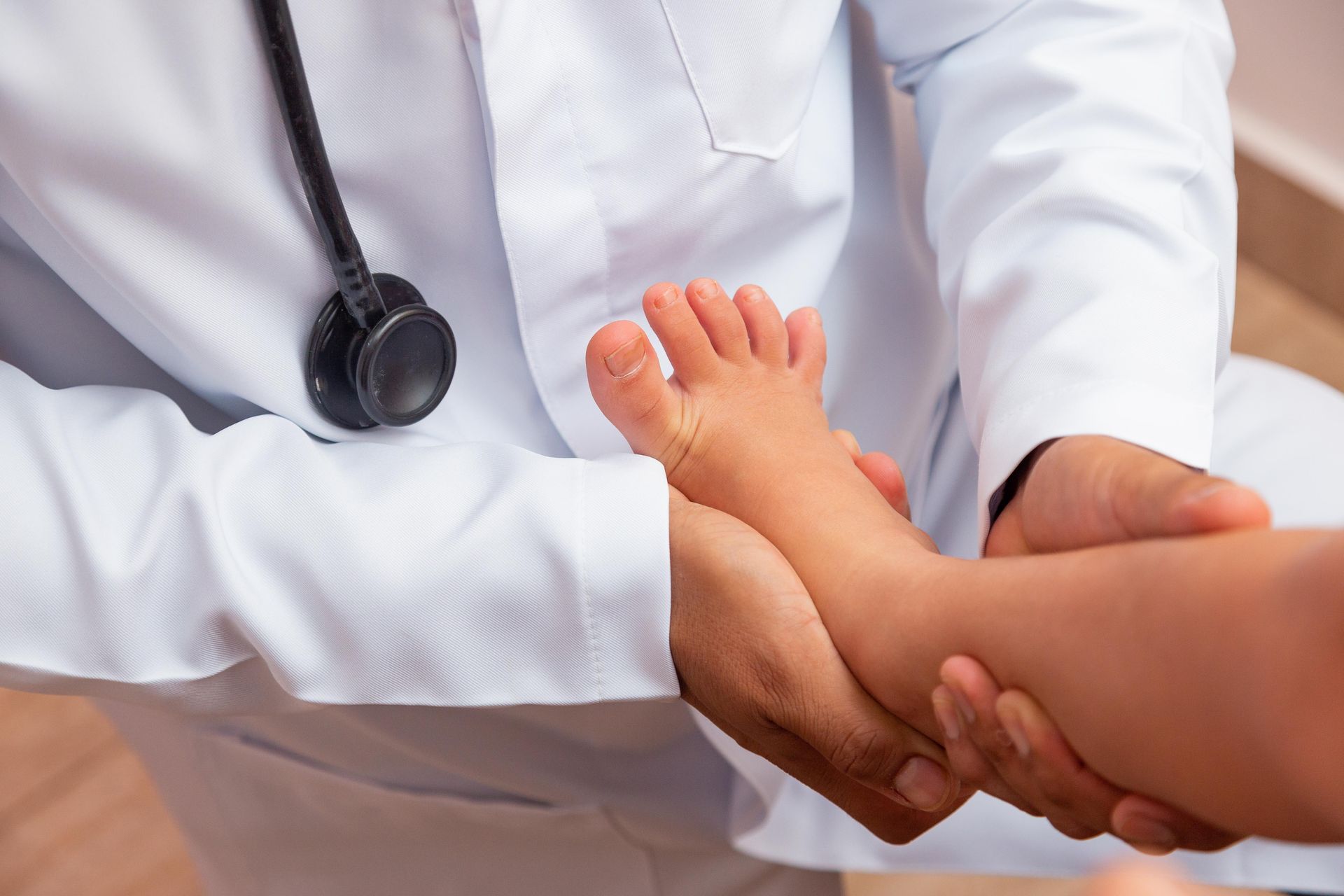Doctor examining a child's foot and ankle, stethoscope visible.