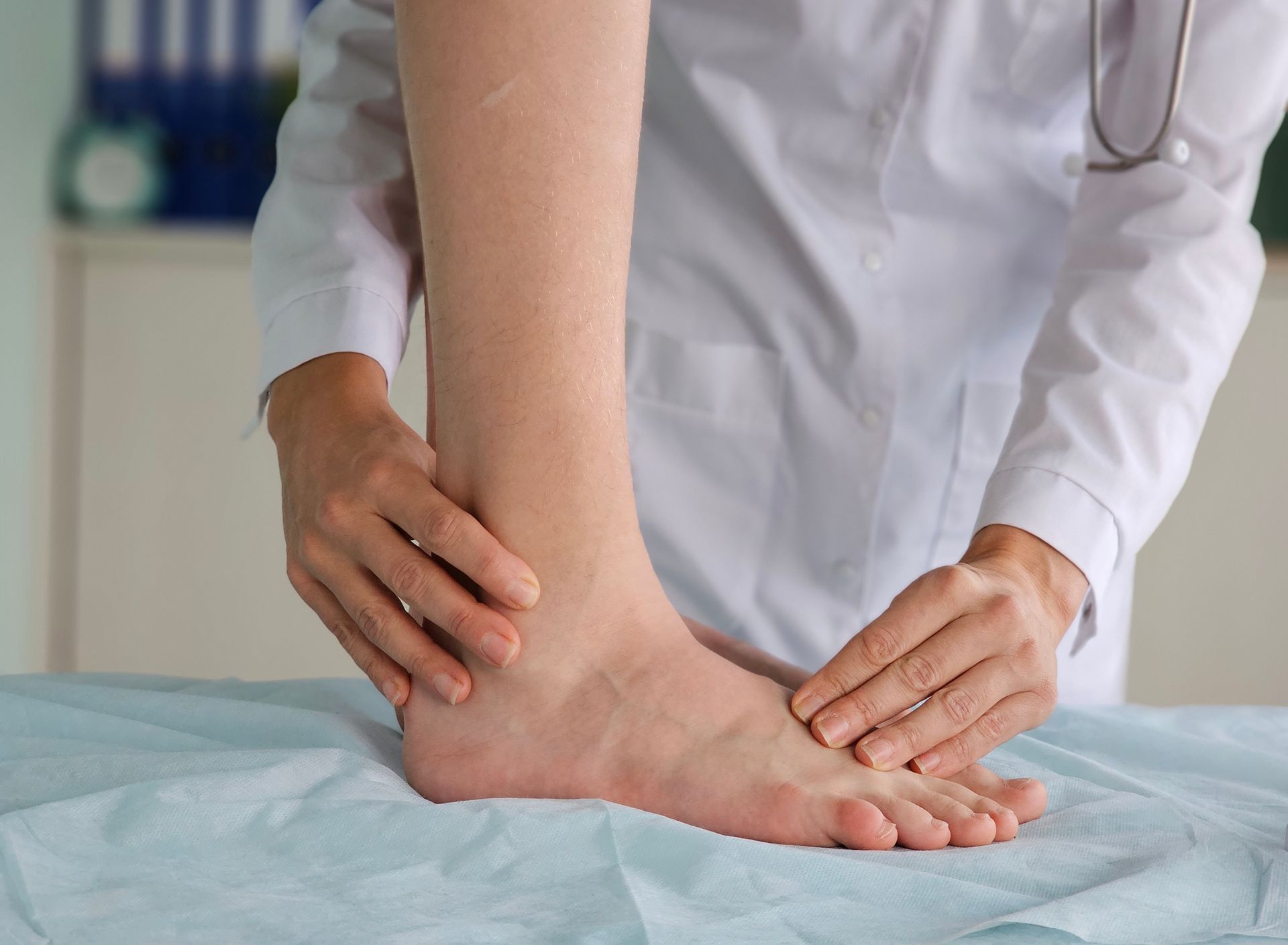 Doctor examining a patient's foot on a medical exam table; a stethoscope is visible.