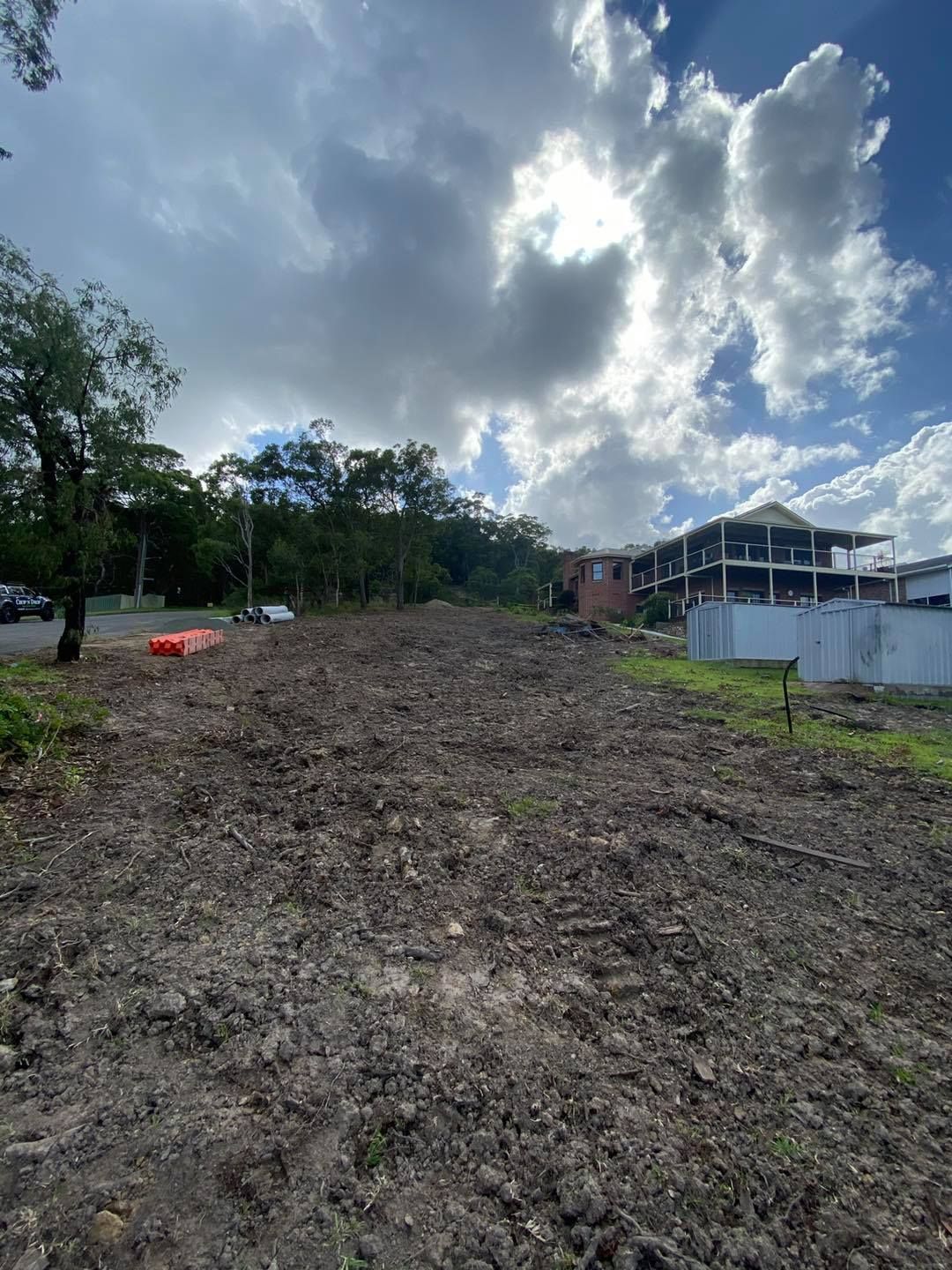 Cleared Lot With Exposed Dirt, Overcast Sky, and Partially Built Building — Chop n Drop Tree Specialists in Cameron Park, NSW