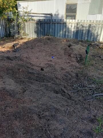 Pile of Dark Mulch in a Backyard, With a Fence and Trailer in the Background — Chop n Drop Tree Specialists in Wallsend, NSW