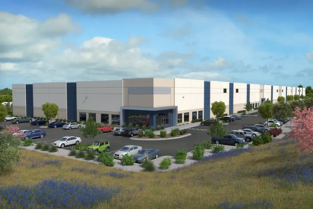 Rendering of a large warehouse with parking, blue accents, and landscaping under a sunny sky.