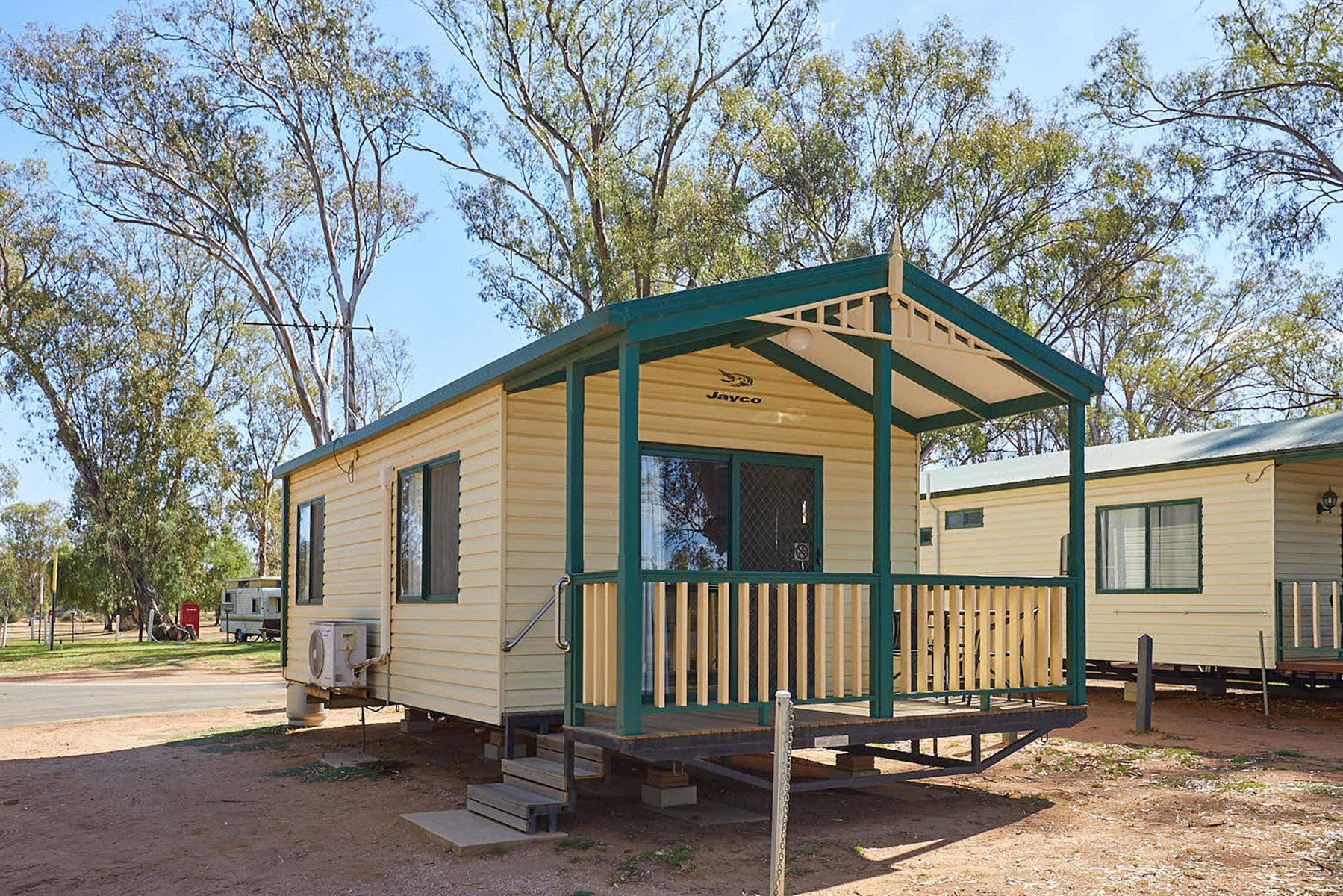 Apex Riverbeach Holiday Park cabin's with a front deck overlooking river beach and trees in the background .