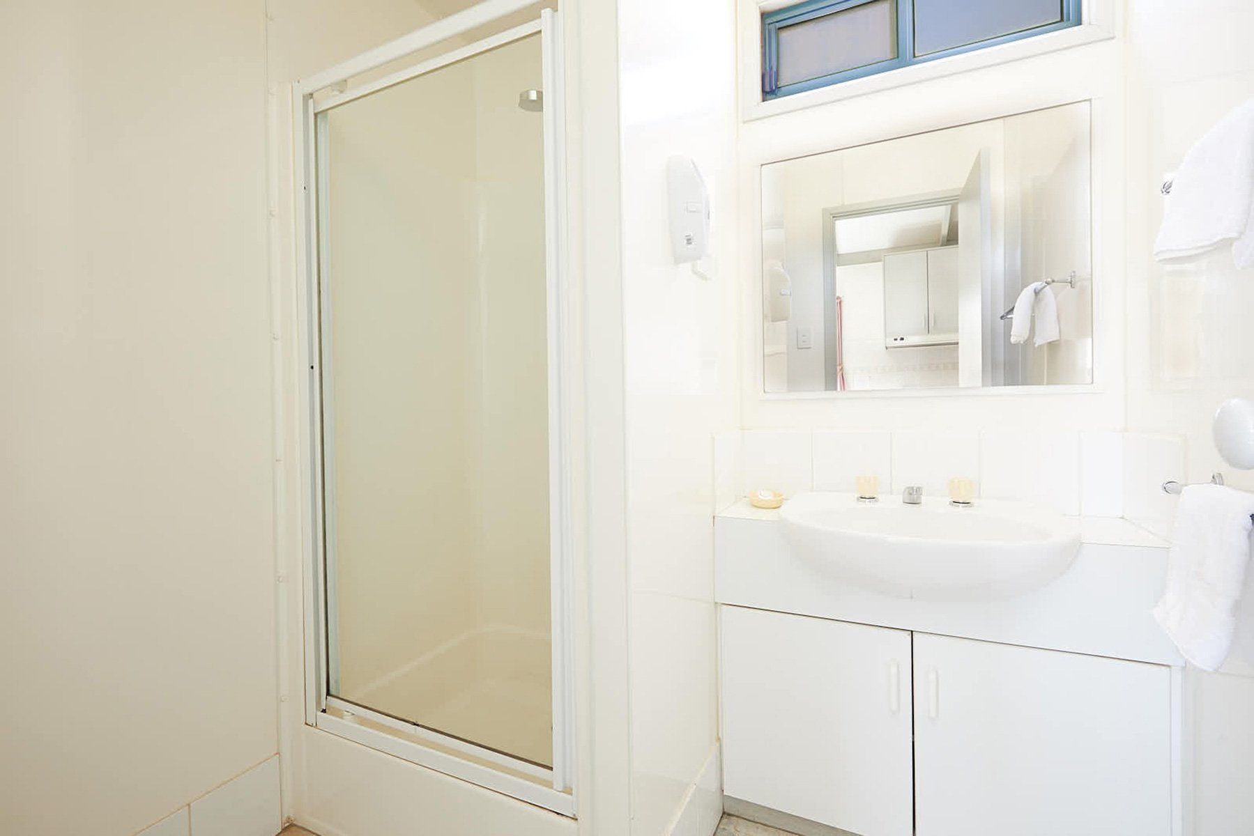 Apex Riverbeach Holiday Park cabin's bathroom with a sink , mirror and shower stall .