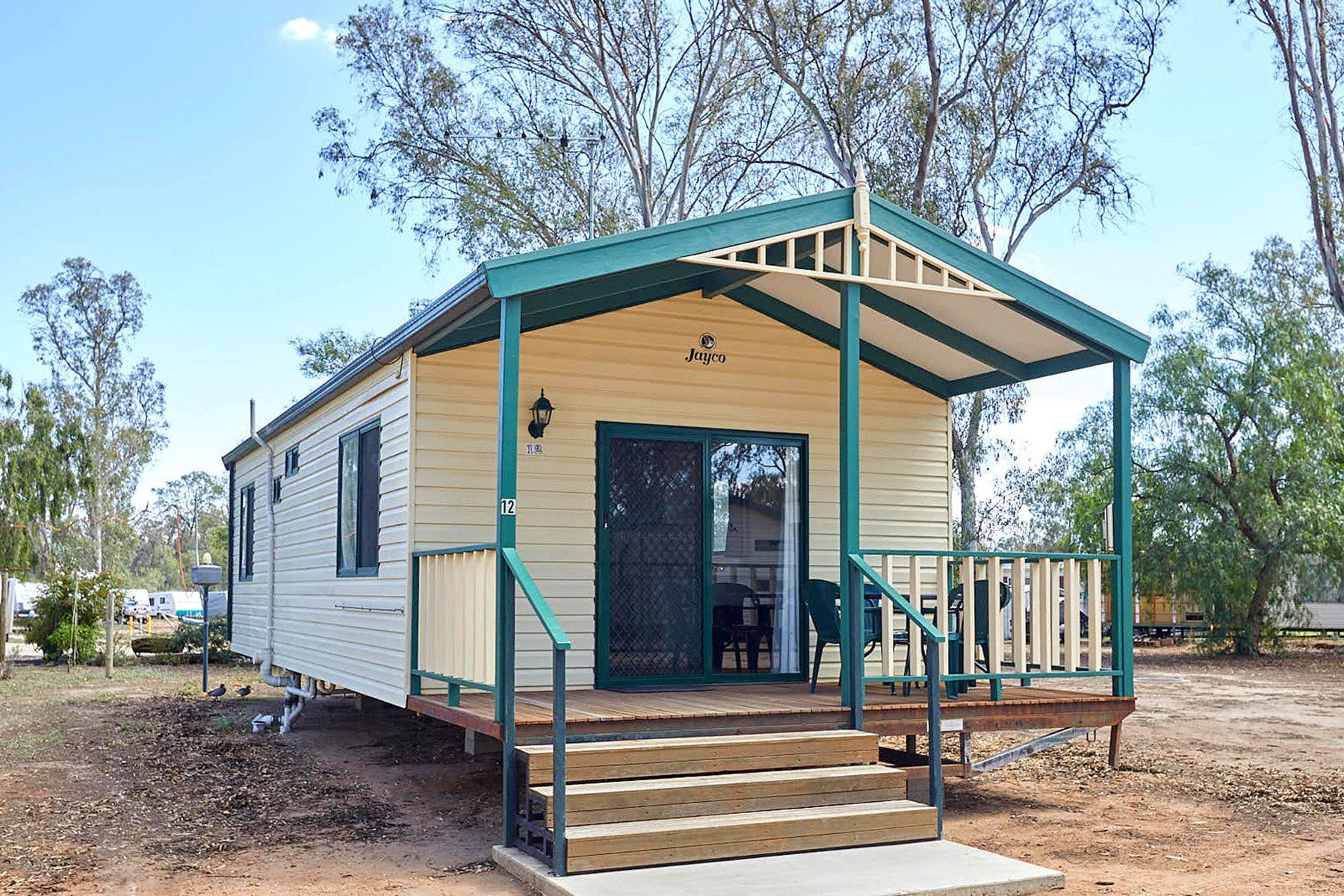 Apex Riverbeach Holiday Park cabin's with a front deck overlooking river beach and trees in the background 