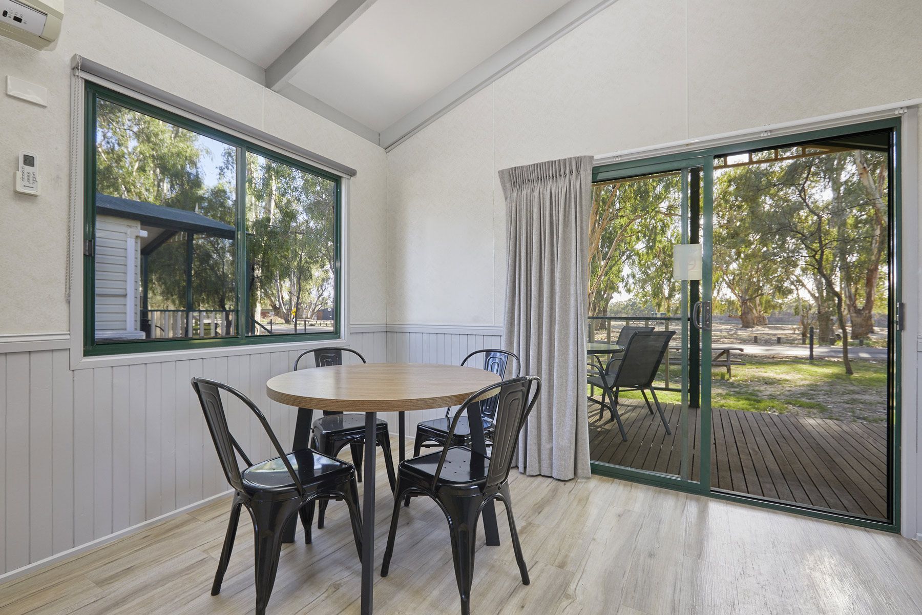 Apex Riverbeach Holiday Park cabin's dining room with table and chairs and a sliding glass door leading to a deck .