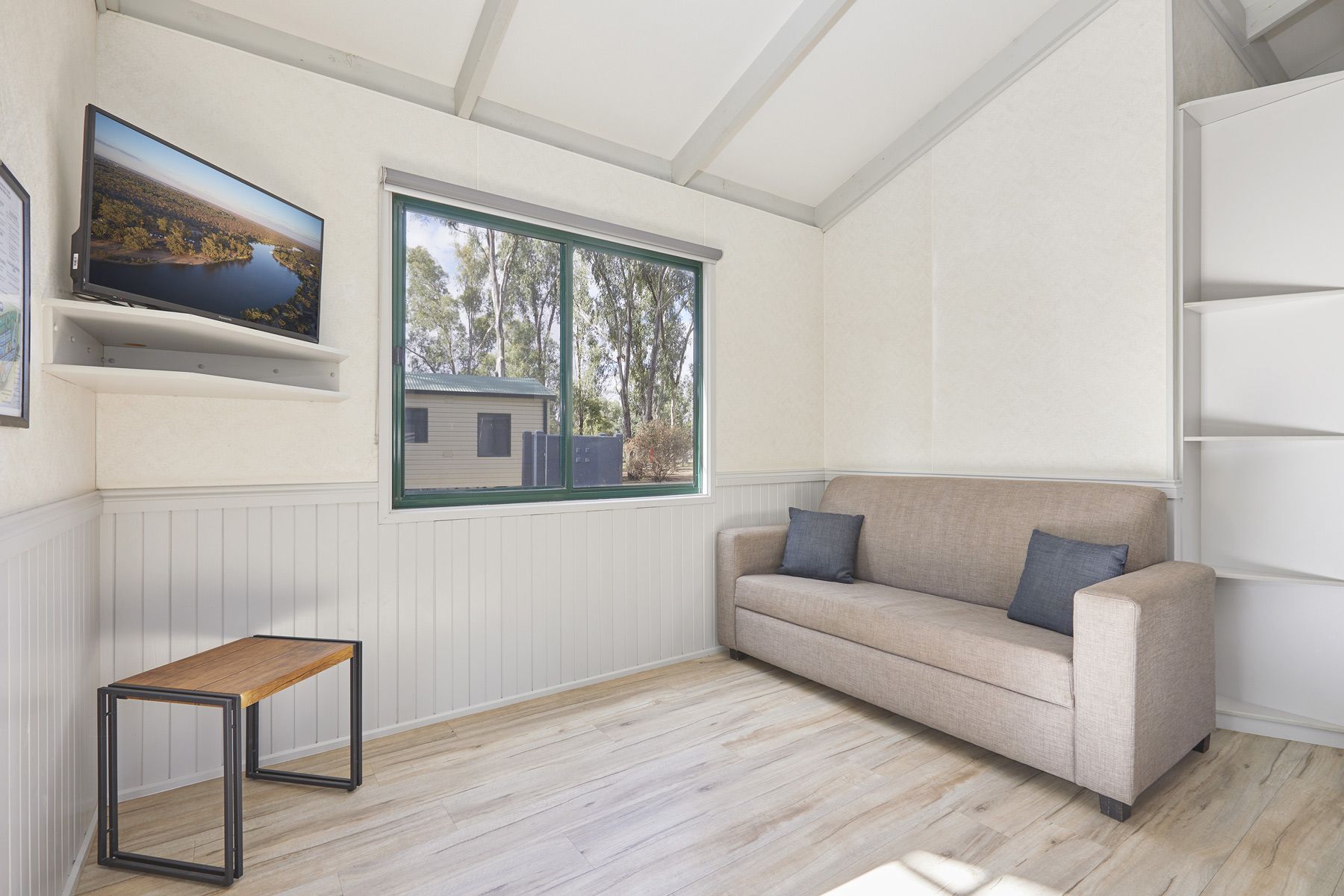 Apex Riverbeach Holiday Park cabin's living room with a couch and a television on the wall .