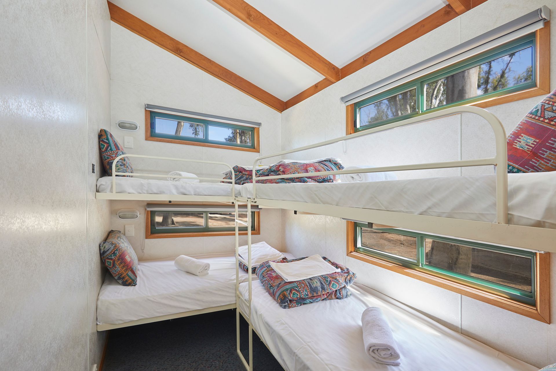 Apex Riverbeach Holiday Park cabin's bedroom with four bunk beds and individual windows .