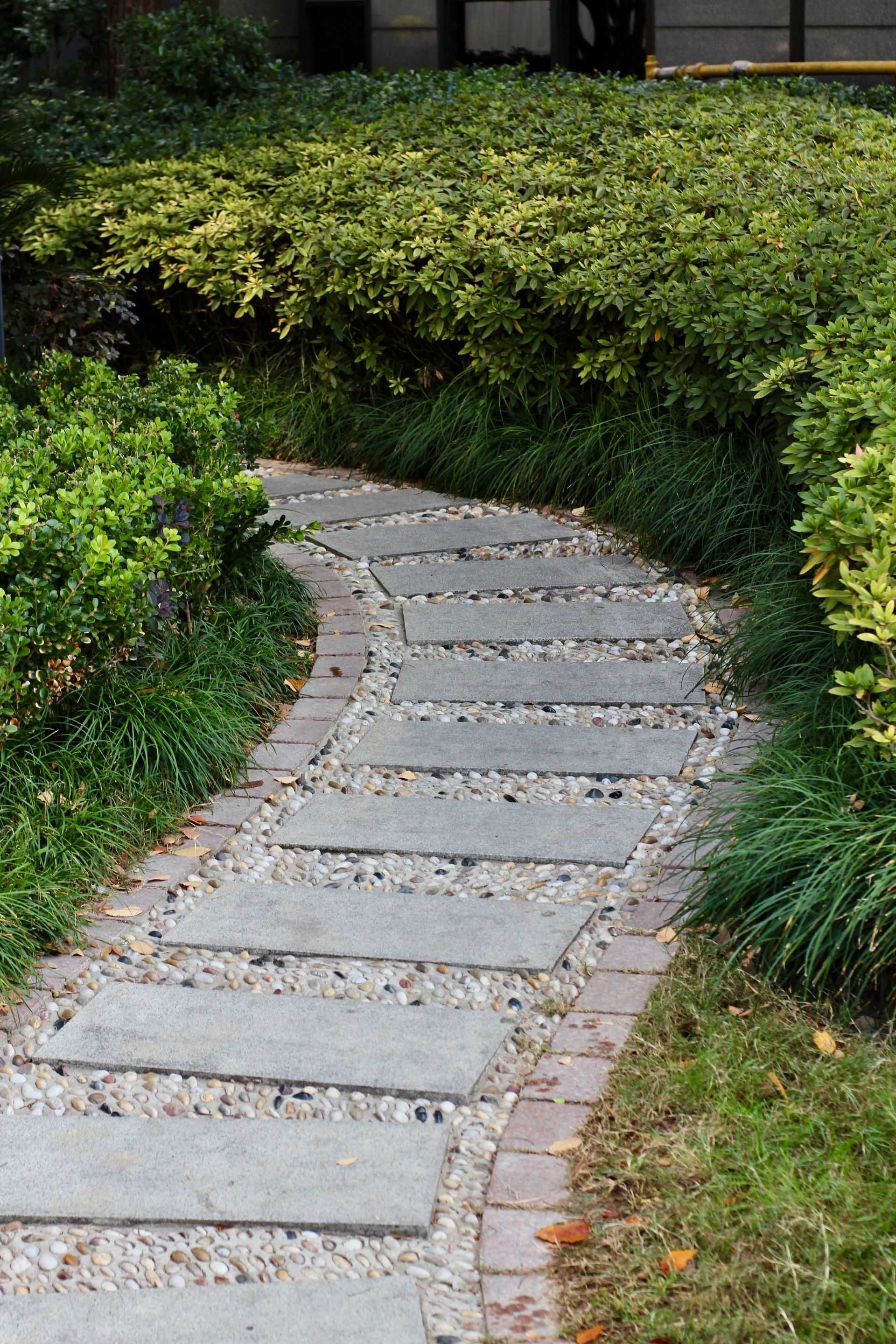 Curved stone garden path bordered by green shrubs and grass