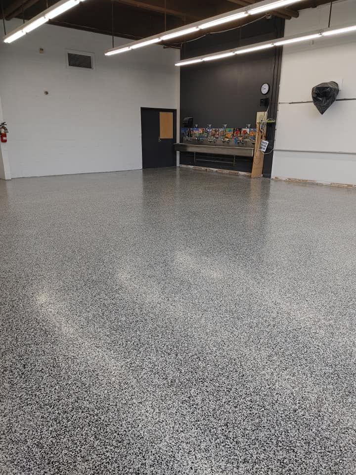 Une grande pièce vide avec un sol gris et des murs blancs.